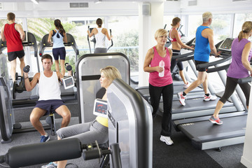 Fototapeta na wymiar Elevated View Of Busy Gym With People Exercising On Machines