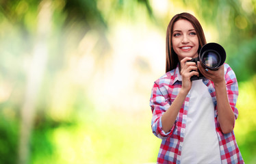 Young female photographer taking photos on nature background