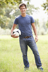 Young Man Holding Soccer Ball In Countryside