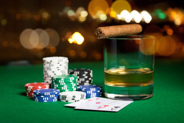 close up of chips, cards whisky and cigar on table
