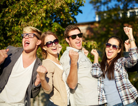 group of happy friends showing triumph gesture