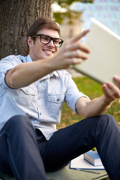 happy teenage boy with tablet pc taking selfie