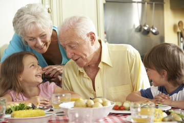 Grandparents And Grandchildren Eating Meal Together In Kitchen - obrazy, fototapety, plakaty