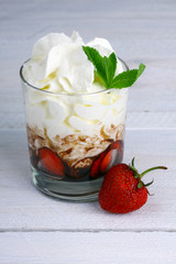 Healthy layered  desserts with fresh strawberries and cream on wooden 