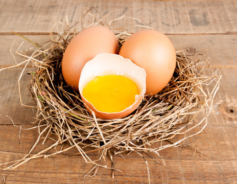 Egg in hay nest on old wooden table background