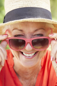 Head And Shoulders Portrait Of Smiling Senior Woman Wearing Sunglasses