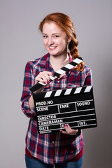 Beautiful smiling red-haired woman holding a movie clapper