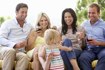 Group Of Friends Sitting On Outdoor Seat Together With Young Girl