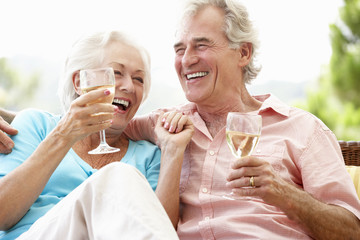 Senior Couple Sitting On Outdoor Seat Together Drinking Wine