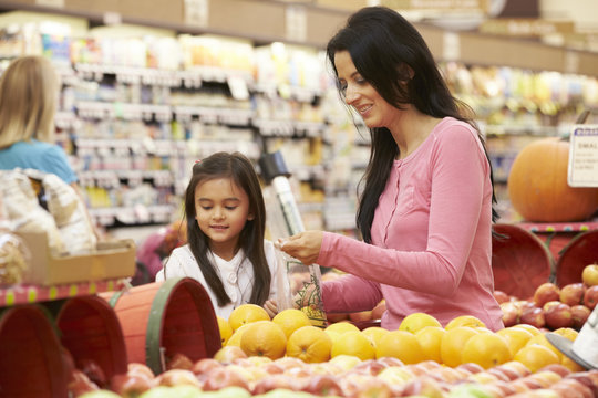 Mother And Daughter At Fruit Counter In Supermarket