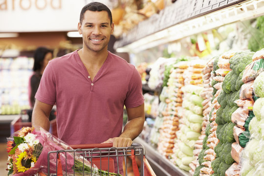 Man Pushing Trolley By Produce Counter In Supermarket