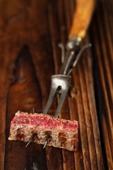 beef steak Slice on vintage meat fork  with dark wooden background