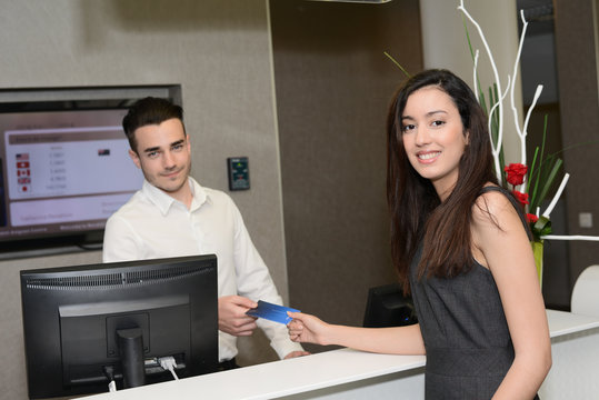 young hotel receptionist handing over room keys to beautiful business woman
