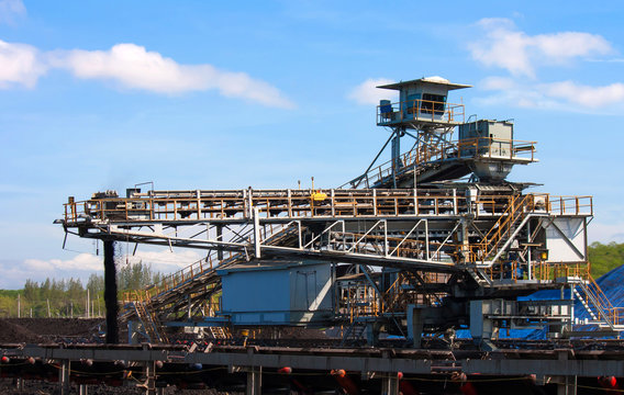 Large conveyor belt carrying coal and emptying onto a huge pile.