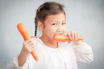 asian little girl hold and eat carrot