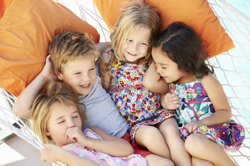 Four Children Relaxing In Garden Hammock Together