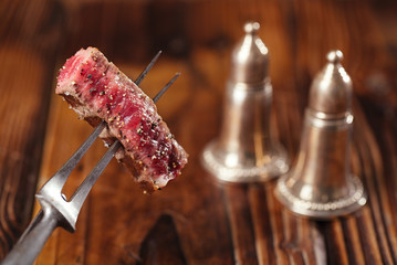 beef steak Slice on vintage meat fork  with dark wooden background