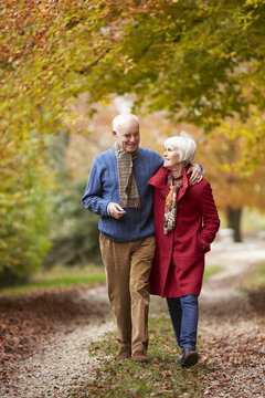 Senior Couple Walking Along Autumn Path