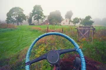 The steering wheel of a car on a background of a village house i