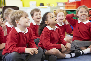 Pupils Sitting On Mat Listening To Teacher