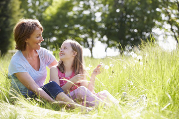 Fototapeta premium Grandmother And Granddaughter Sitting In Summer Field