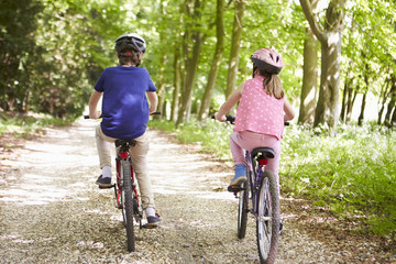 Fototapeta na wymiar Rear View Of Two Children On Cycle Ride In Countryside