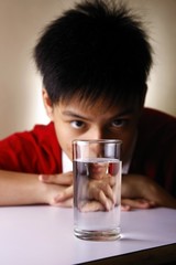 Teen looking at a glass of water on a wooden table