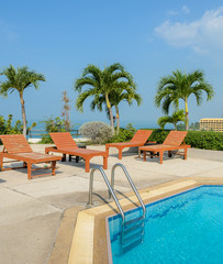 Swimming pool with wooden sun loungers