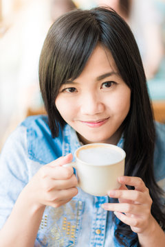 Happy asian young woman sitting in vintage cafe with cup of coff