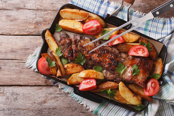 Pork ribs with baked potatoes in a pan closeup. horizontal top view
