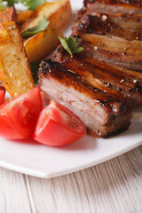 roasted pork ribs, potatoes and tomatoes macro. vertical
