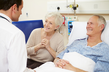 Fototapeta premium Doctor Talking To Senior Couple By Hospital Bed