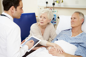 Obraz premium Lekarz Z Cyfrowego Tabletu Rozmawia Z Parą Przy łóżku Szpitalnym