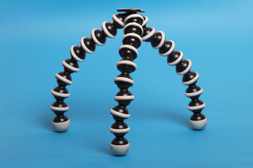 Close up view of a gorilla pod type tripod isolated on a blue background.
