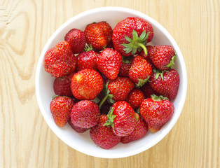 red strawberries in plate isolated on wooden table