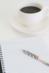 Coffee cup with note book and pencil