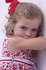 Portrait of an angry girl, leaning against a wall 