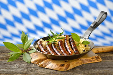 Leckere Rostbratwürste auf Sauerkraut in der Eisenpfanne serviert