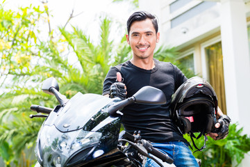 Asian young man and his motorcycle or scooter