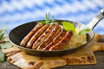 Leckere Rostbratwürste auf Sauerkraut in der Eisenpfanne serviert