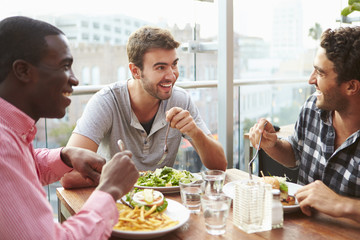Three Male Friends Enjoying Lunch At Rooftop Restaurant