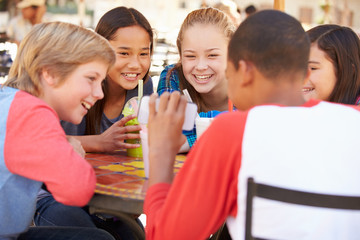 Group Of Children In CafÅ½ Looking At Text On Mobile Phone