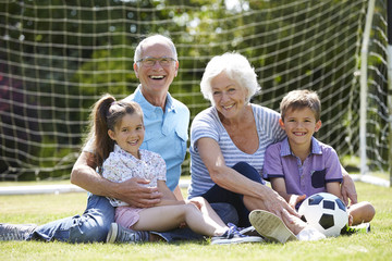 Grandparents And Grandchildren Playing Football In Garden