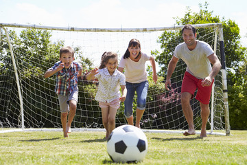 Family Playing Football In Garden Together