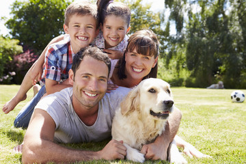 Family Relaxing In Garden With Pet Dog