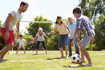 Multi Generation Playing Football In Garden Together - Powered by Adobe