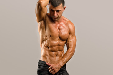 Fototapeta premium Strong bodybuilder with six pack.Strong bodybuilder man with perfect abs, shoulders,biceps, triceps and chest, personal fitness trainer flexing his muscles