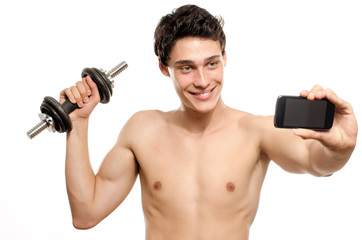 Fototapeta na wymiar Skinny man taking a selfie with his phone while training his bicep muscle. Beautiful teenager lifting a dumbbell and taking a photo for facebook.Anorexic young man training to become stronger