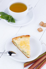Tasty slice of rhubarb pie on white wooden table.
