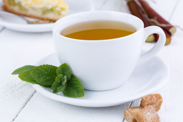 Mint tea with slice of rhubarb pie on wooden table.